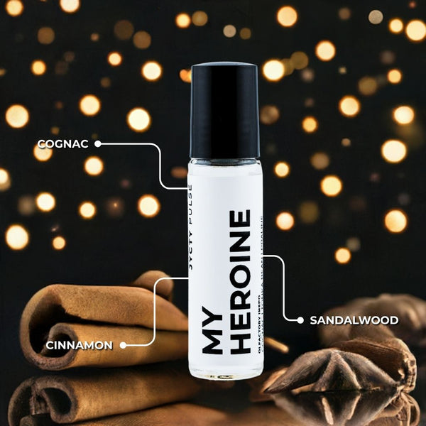 Bottle of 'My Heroine' with cinnamon sticks and sandalwood on a dark background with glowing lights.