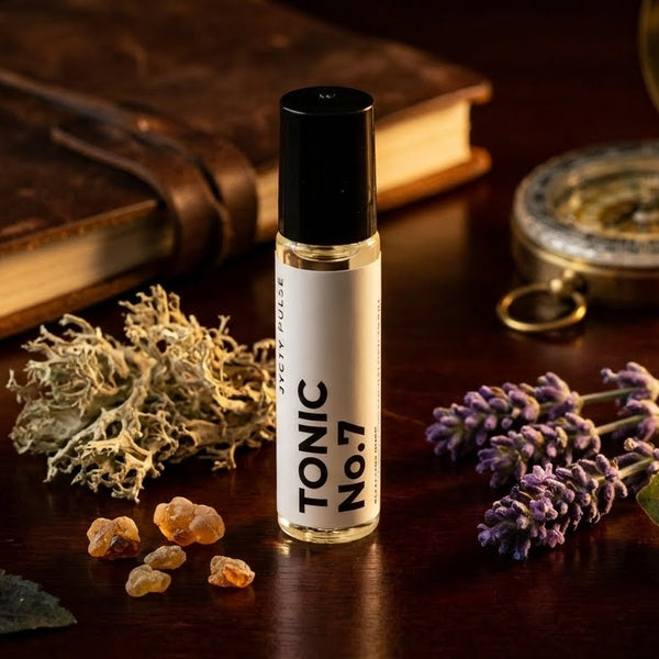 Tonic No.7 rollerball with herbs and a book on a wooden surface